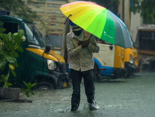 A man walks along a flooded street under heavy rains in Chennai as cyclone Nivar approaches the southeastern coast of the country on November 25, 2020. (Photo by Arun SANKAR / AFP)