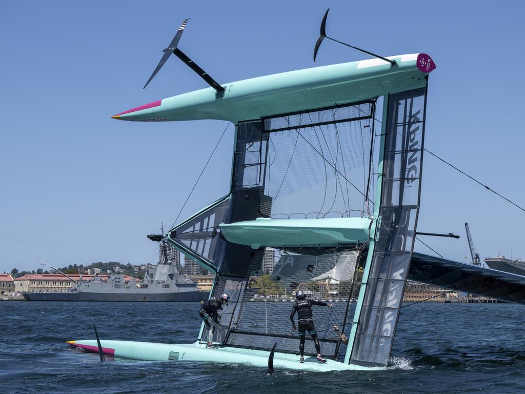 Taylor Canfield clings to the hull of his capsized American F50 Photo: Ricardo Pinto for SailGP. Handout image supplied by SailGP