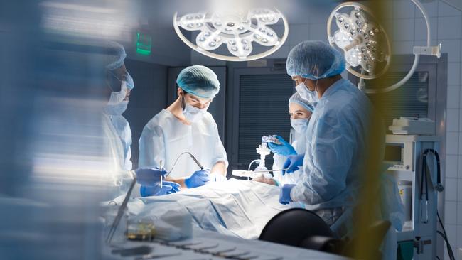 Blurred shot of group of professional surgeons at work in operating room. Emergency case, surgery, medical technology, health care cancer and disease treatment concept