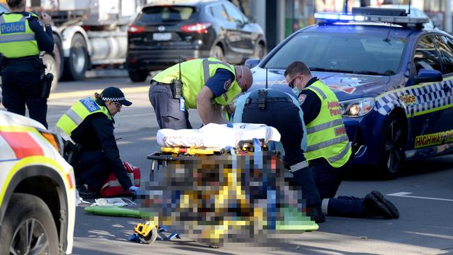 Paramedics tend to an injured man after he was struck by a car on Bridge Rd, Richmond.