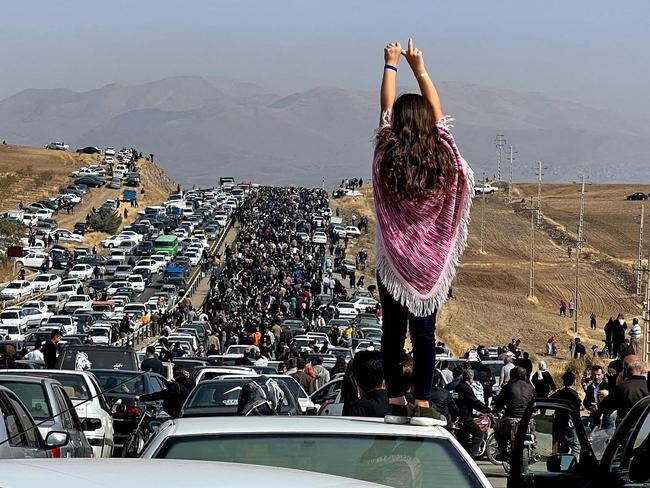 -- AFP PICTURES OF THE YEAR 2022 --  This UGC image posted on Twitter reportedly on October 26, 2022 shows an unveiled woman standing on top of a vehicle as thousands make their way towards Aichi cemetery in Saqez, Mahsa Amini's home town in the western Iranian province of Kurdistan, to mark 40 days since her death, defying heightened security measures as part of a bloody crackdown on women-led protests. - A wave of unrest has rocked Iran since 22-year-old Amini died on September 16 following her arrest by the morality police in Tehran for allegedly breaching the country's strict rules on hijab headscarves and modest clothing. (Photo by UGC / AFP) / AFP PICTURES OF THE YEAR 2022  === RESTRICTED TO EDITORIAL USE - MANDATORY CREDIT "AFP PHOTO / UGC IMAGE" - NO MARKETING NO ADVERTISING CAMPAIGNS - DISTRIBUTED AS A SERVICE TO CLIENTS FROM ALTERNATIVE SOURCES, AFP IS NOT RESPONSIBLE FOR ANY DIGITAL ALTERATIONS TO THE PICTURE'S EDITORIAL CONTENT, DATE AND LOCATION WHICH CANNOT BE INDEPENDENTLY VERIFIED === /