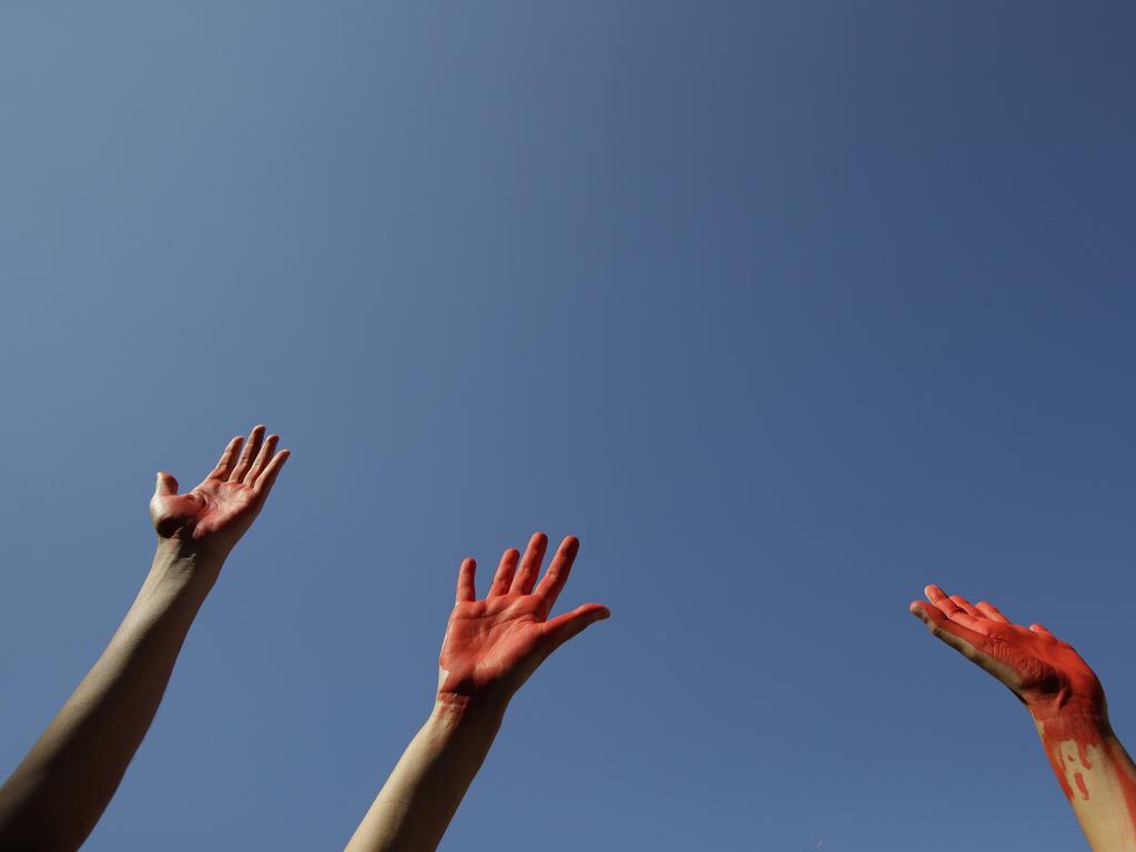 People with hands painted in red protest in front of the Italian Interior Ministry headquarters in Rome, Wednesday, July 18, 2018. Dozens of protesters marched in front of the ministry to protest government's hard-line immigration policy. (AP Photo/Alessandra Tarantino)
