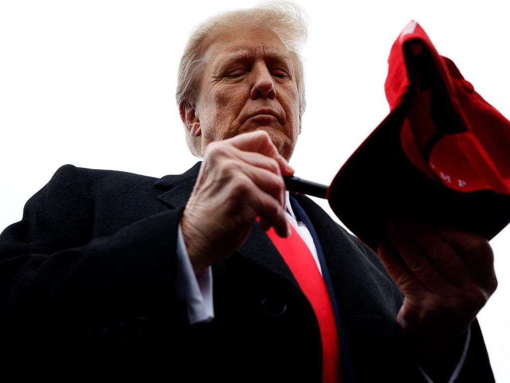 Republican presidential candidate Donald Trump autographs hats while chatting with supporters outside the polling site at Londonderry High School in New Hampshire. Picture: Getty Images