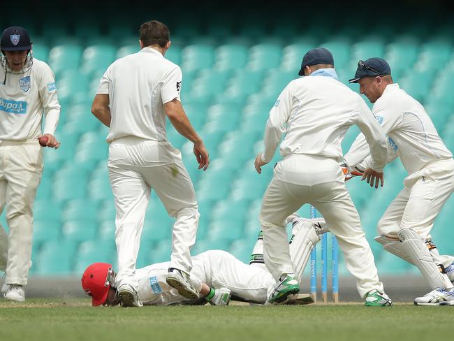 Hughes collapses in the middle of a group of NSW players.