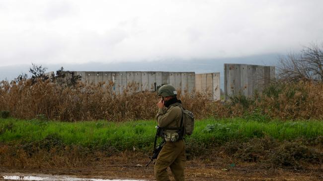 An Israeli soldier walks past a border fence with Lebanon near the northern kibbutz of Kfar Blum. Picture: Jalaa Marey / AFP