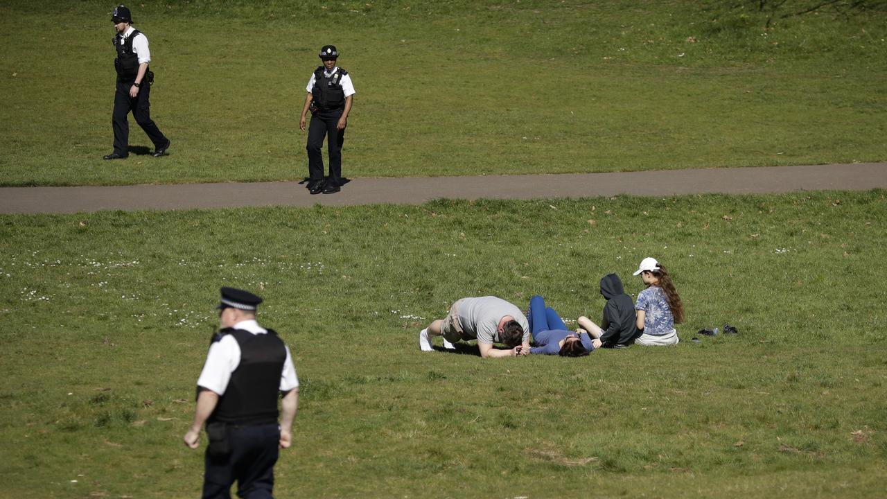 Police officers ask people sitting down on the grass to move on in Greenwich Park, London. Matt Dunham/AP