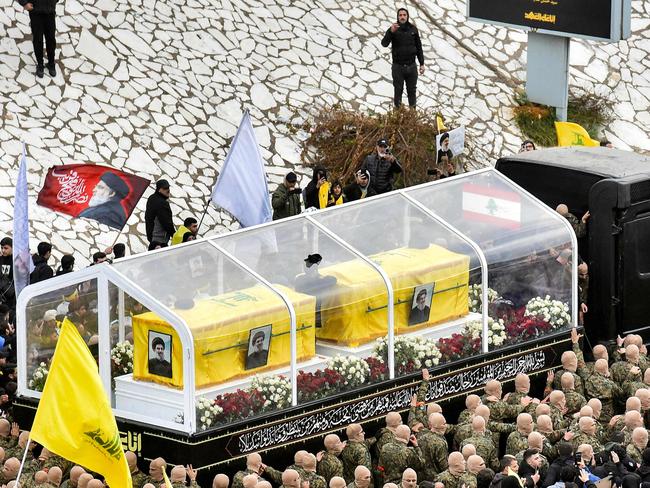 Mourners walk during the funeral procession with the vehicle carrying the coffins of Hezbollah's slain leaders Hassan Nasrallah and Hashem Safieddine from the Camille Chamoun Sports City Stadium towards the burial place on the outskirts of Beirut on February 23, 2025. Tens of thousands of mourners dressed in black vowed support for Hezbollah at the Beirut funeral of slain leader Hassan Nasrallah, after the group was dealt major blows in its last round of hostilities with Israel. The September killing of the charismatic leader, who led Hezbollah for more than three decades, in a massive Israeli strike dealt a heavy blow to the Iran-backed group. (Photo by Fadel ITANI / AFP)