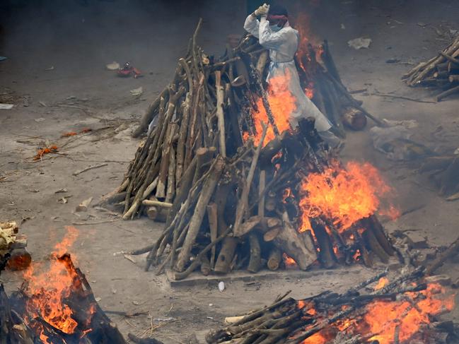 A volunteer walks past burning pyres in New Delhi. Picture: AFP.