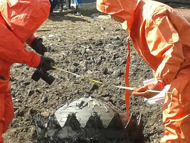 Chinese Government technicians prepare to remove space debris that fell out of the sky, crashing to the ground.