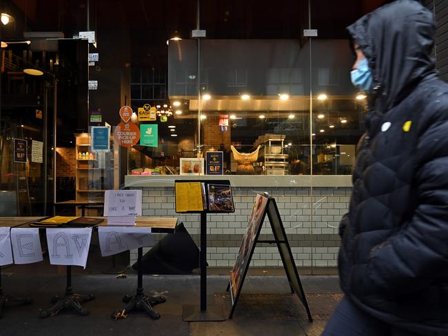 EMBARGO FOR TWAM 21 AUG 2021  SYDNEY, AUSTRALIA - July 14: A person wearing a mask walks past an empty restaurant offering takeaway in the Sydney CBD, during lockdown in Sydney, Australia, Wednesday, July 14, 2021. CR Getty Images