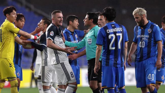 The referee talks to Melbourne Victory striker Besart Berisha as players remonstrate on Wednesday night.