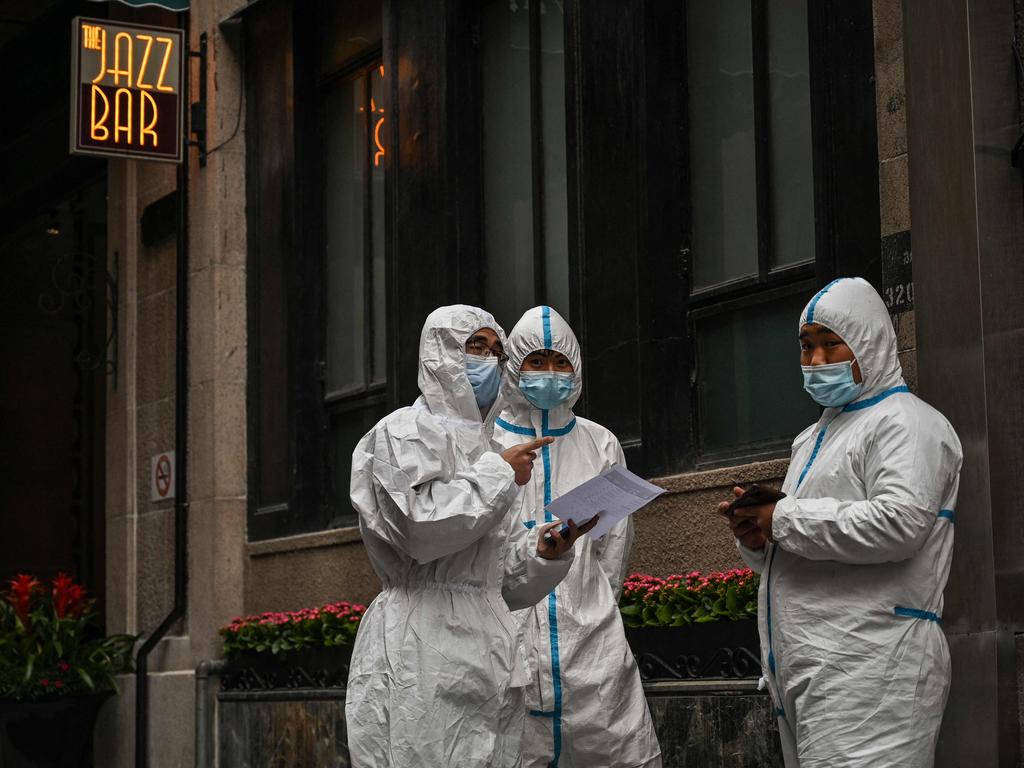 Workers, wearing protective gear, stand next to the access of a Hotel on the Bund, in the Puxi area that will be in lockdown from April 1, in Shanghai. Picture: Hector Retamal / AFP.