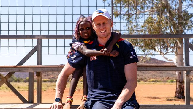 Adelaide Crows player Reilly O’Brien and little girl Zendaya during the club's APY Lands trip September 2023. Picture: Laura Chigwidden/AFC