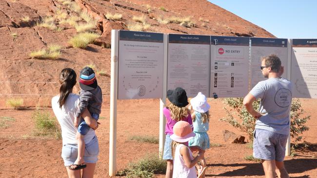 Tourists reading the Anangu plea to stay off Uluru. Picture: Zach Hope