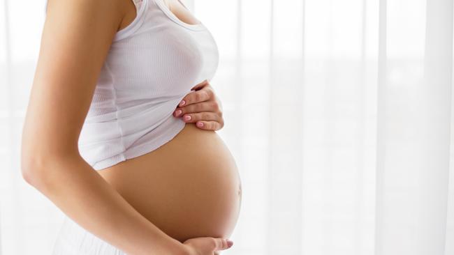 Pregnant woman standing next to window