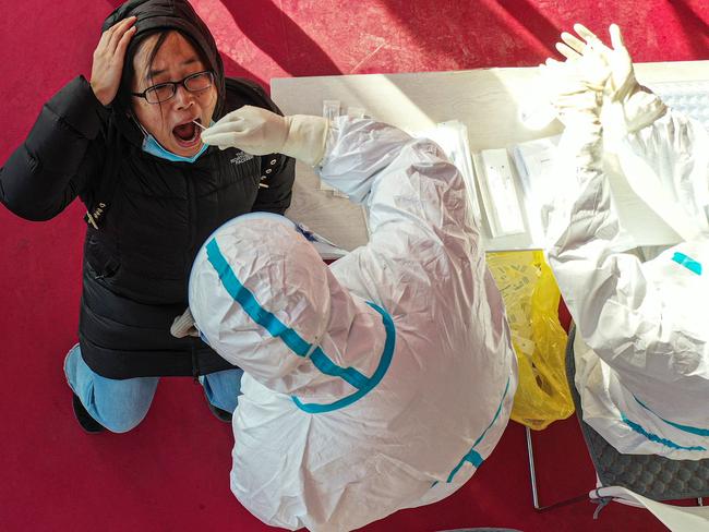 This photo taken on January 2, 2021 shows a health worker taking a swab sample from a resident, to be tested for the Covid-19 coronavirus at a temporary testing centre in Shenyang, in China's northeast Liaoning province. (Photo by STR / AFP) / China OUT