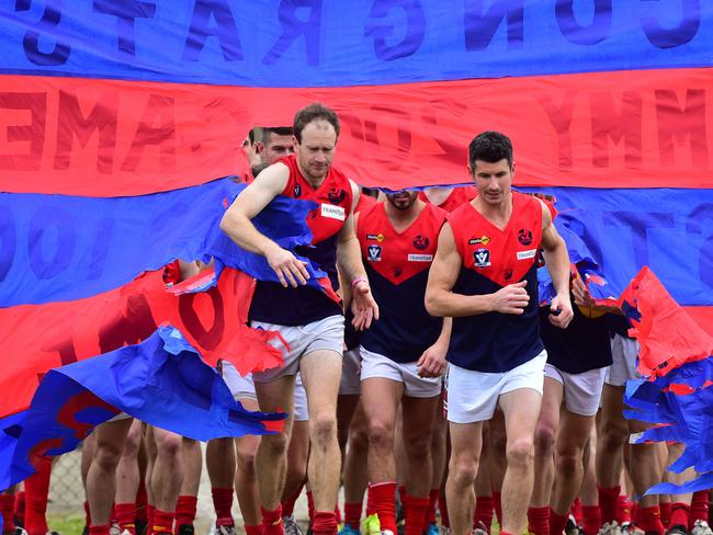 Mt Eliza teammates Tim Strickland, left, and James Clayton burst through the banner before their 100th and 200th games respectively on Saturday. Picture: Derrick den Hollander