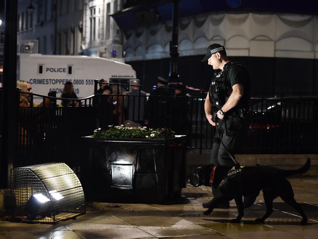 A police officer and his sniffer dog inspect the scene near the remains of the car that was earlier hijacked and packed with explosives before being detonated outside Derry court house. Picture: Getty