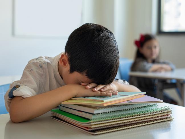 Young boy sleeping at her desk in a classroom