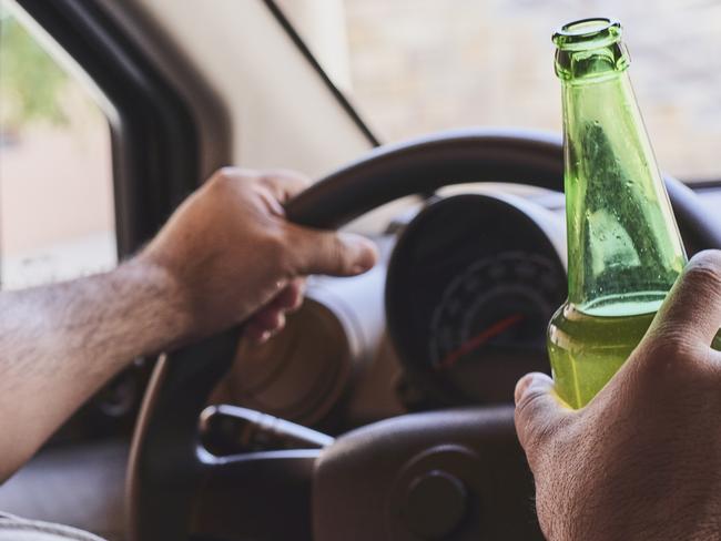 An unrecognizable man drinking beer while driving car. Concepts of driving under the influence, drunk driving or impaired driving. Drink driving generic. Picture: iSTOCK