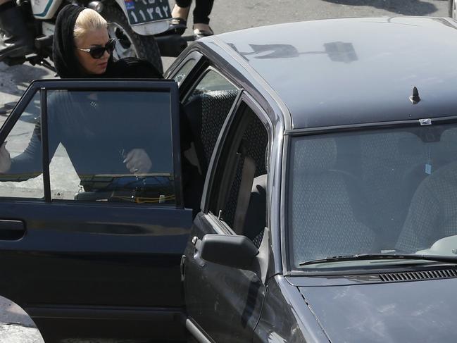 An Iranian woman gets into a private car serving as an unofficial taxi in Tehran's northwestern Punak neighbourhood on October 4, 2016. Tehran already has 78,000 official taxis -- more than five times the number in New York -- and another 35,000 agency cabs. Travelling one kilometre (just over half a mile) up Valyasr Street -- the main north-south artery -- can take more than an hour once rush-hour kicks in at around 4 pm. / AFP PHOTO / ATTA KENARE / TO GO WITH AFP STORY BY ALI NOORANI AND ERIC RANDOLPH