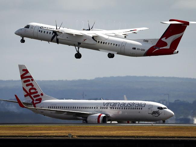 A Virgin Airways plane travels down the runway as a QantasLink Dash 8-400 series plane takes off at Sydney's Kingsford Smith international airport on November 3, 2023. (Photo by DAVID GRAY / AFP)