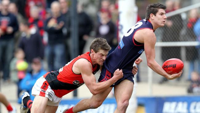 Norwood's Andrew Kirwan dishes out a handball despite a strong tackle from West Adelaide's Jonathon Beech. 