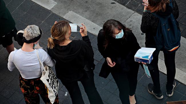 People hand out face masks and sanitiser in Sydney. Picture: Adam Yip