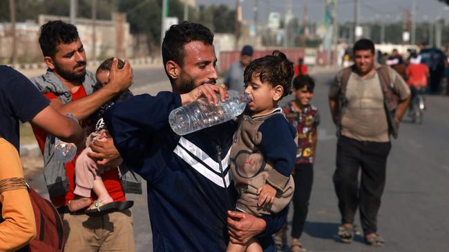 A man helps a toddler drink some water in the Gaza Strip. Picture: AFP