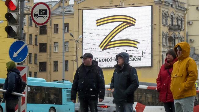 Pedestrians cross a street in front of a billboard displaying the symbol "Z" and a slogan reading: "We don't give up on our people", in support of the Russian armed forces, in Saint Petersburg, on March 7. Picture: AFP