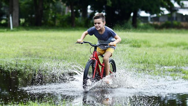 Wet weather in Far North Queensland is expected to peak on Friday night before scattered showers hit through the weekend. Hunter Cairns, 9, rides his new bike through large puddles caused by heavy rainfall at Holloways Beach. Picture: Brendan Radke