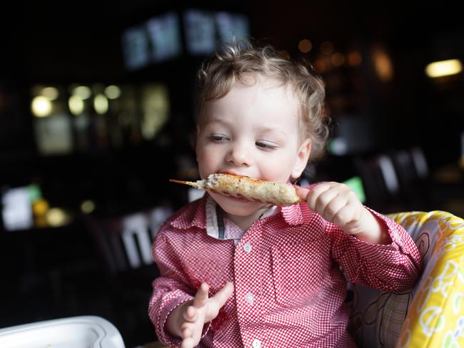 Boy is eating kebab in a high chair at a restaurant
