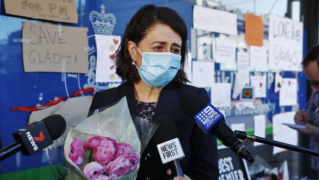 Former NSW premier Gladys Berejiklian clutches some of the many flowers left by her supporters at her electoral office in Willoughby in Sydney. Picture: Sam Ruttyn