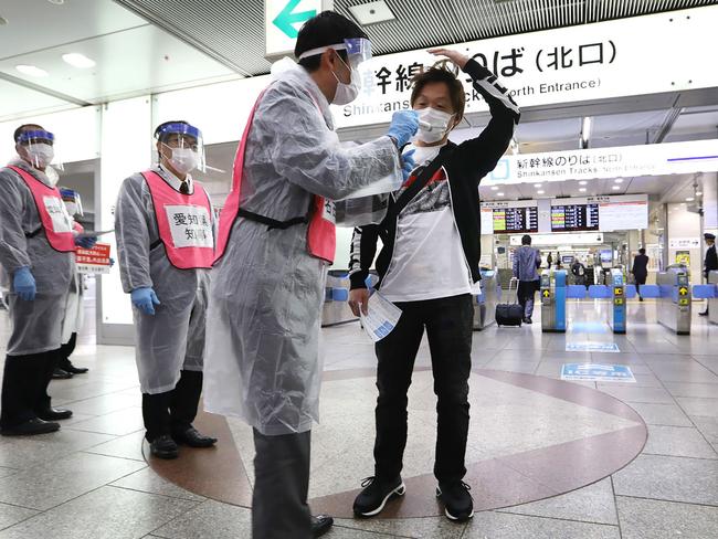 A staff member of Aichi Prefecture checks the body temperature of a passenger arriving at Nagoya railway station in Japan. Picture: Jiji Press