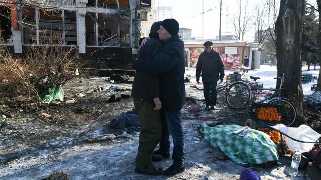 Two men console each other in the aftermath of the deadly strike on the market in Donetsk on Sunday. Picture: AFP