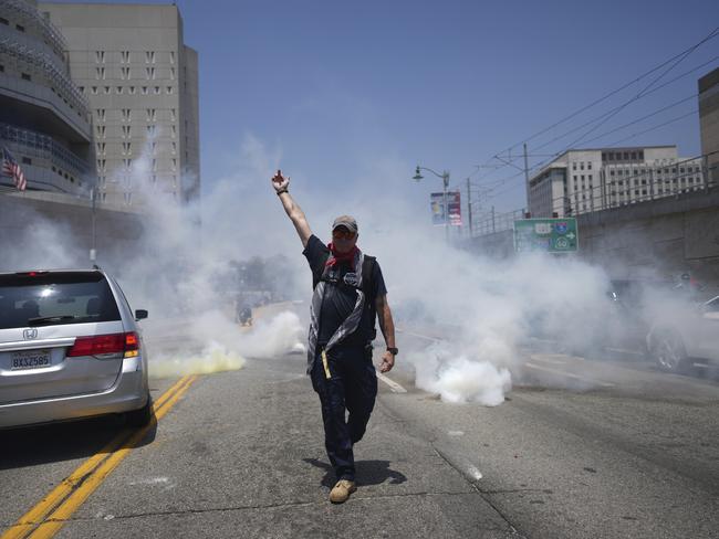 A protester displays a poster as tear gas is used in the metropolitan detention centre of downtown Los Angeles. Picture: AP