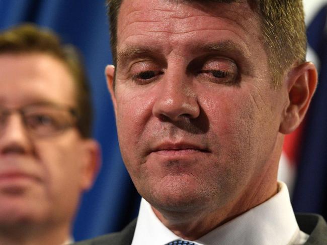 New South Wales Premier Mike Baird (R) speaks as deputy premier Troy Grant (L) listens during a press conference in Sydney on October 11, 2016, after his goverment made an embarrassing backflip on its plan to ban greyhound racing after sustained industry and public pressure, admitting it "got it wrong". Baird announced in July 2016 that his government would shut down the sport from July 1 next year after a series of scandals including "live baiting" and the slaughter of tens of thousands of dogs. / AFP PHOTO / WILLIAM WEST