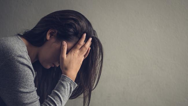 Depressed woman sitting on a chair in dark room at home. Lonly, sad, emotion concept.