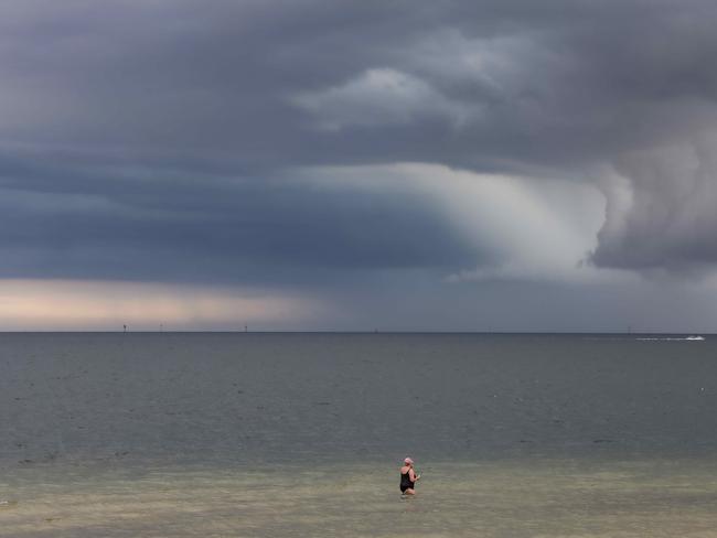 A woman takes a swim at South Melbourne beach as a storm approaches. Picture: Ian Currie