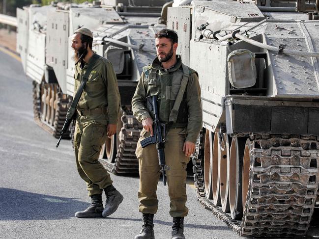 Israeli army soldiers walk before tracked vehicles deployed at a position in the Upper Galilee region in northern Israel near the border with southern Lebanon on October 24, 2023. (Photo by Jalaa MAREY / AFP)