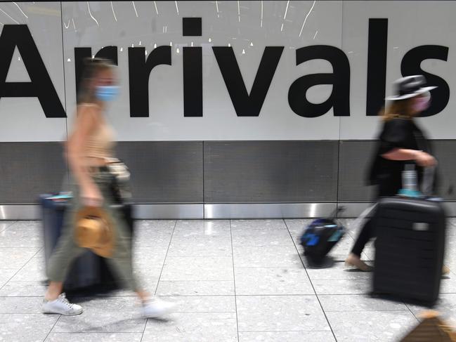 Passengers wearing face masks as a precautionary measure against COVID-19, walk through the arrivals hall after landing at London Heathrow Airport in west London, on January 15, 2021. - International travellers will need to present proof of a negative coronavirus test result in order to be allowed into England, or face a Â£500 ($685, 564 euros) fine on arrival, from January 18. (Photo by DANIEL LEAL-OLIVAS / AFP)