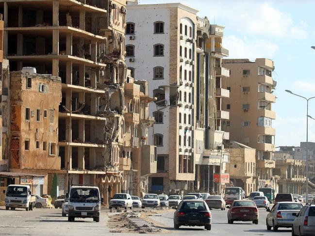 Cars drive past heavily damaged buildings in Libya's eastern city of Benghazi on April 8, 2019. - Vowing to "cleanse" the country of jihadists, Libyan strongman Khalifa Haftar's forces pushed hardline militias out of the eastern city of Benghazi in 2017 after a deadly three-year battle dubbed "Operation Dignity". Haftar's forces launched an offensive against the capital Tripoli on April 5, 2019. (Photo by Abdullah DOMA / AFP)