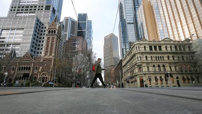 A man crossing the lights in an empty Melbourne. Picture: Ian Currie