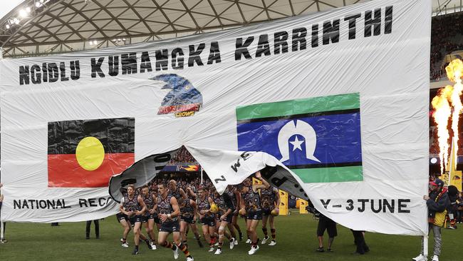 Taylor Walker leads the Adelaide Crows through the banner for the 2019 AFL Indigenous round. Picture Sarah Reed