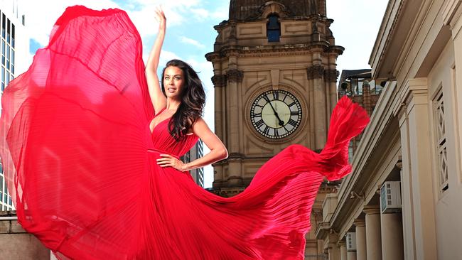 Model Megan Gale was seeing red when she whirled her gown around on the roof of Melbourne Town Hall in preparation for the launch of Melbourne Fashion Week. Picture: Alex Coppel