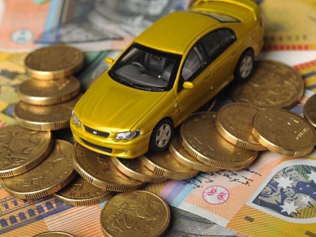 How to cut your car costs - Toy matchbox cars pictured with piles of money. Coins and notes arranged as roads and obstacles for the toy cars to drive over.