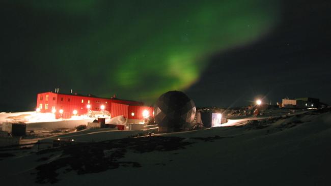 Mawson base in the East Antarctic region with the Aurora Australis lighting the sky behind it.