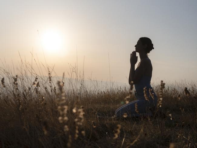 Side view of silhouette woman praying against sky during sunset