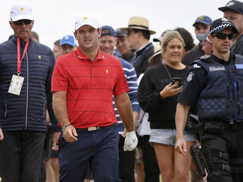 Reed is escorted by security and police down a fairway. Picture: AFP
