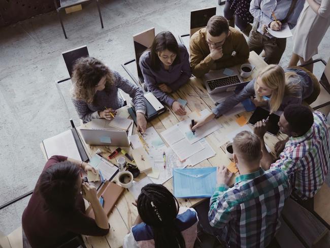 Top view of creative business team sitting at the table at loft office and working. Woman manager brings the document to mixed race group of people. Colleagues discussing the project. Picture: iStock